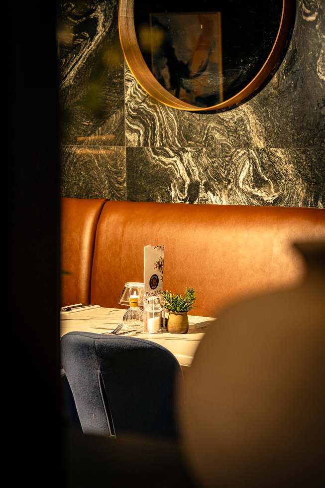 Booth seating beside a marble wall at Pradas